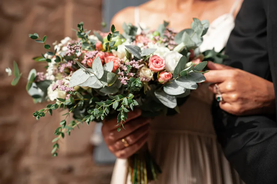 Bouquet de roses et d'eucalyptus tenu par la mariée